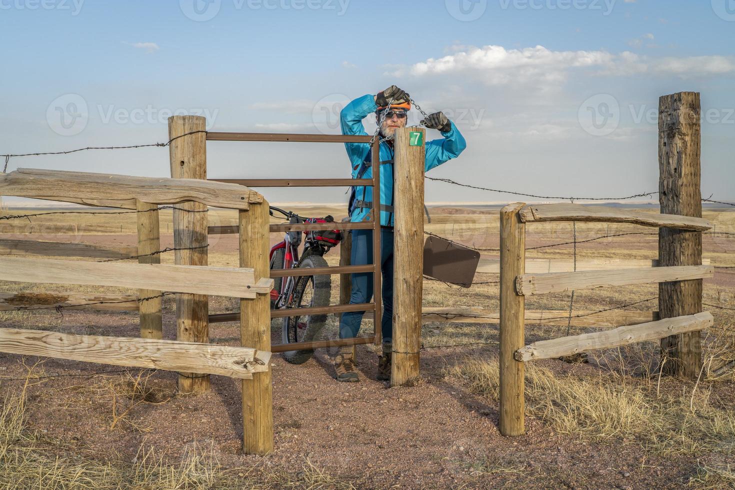 cyclist closing a gate in cattle fence photo