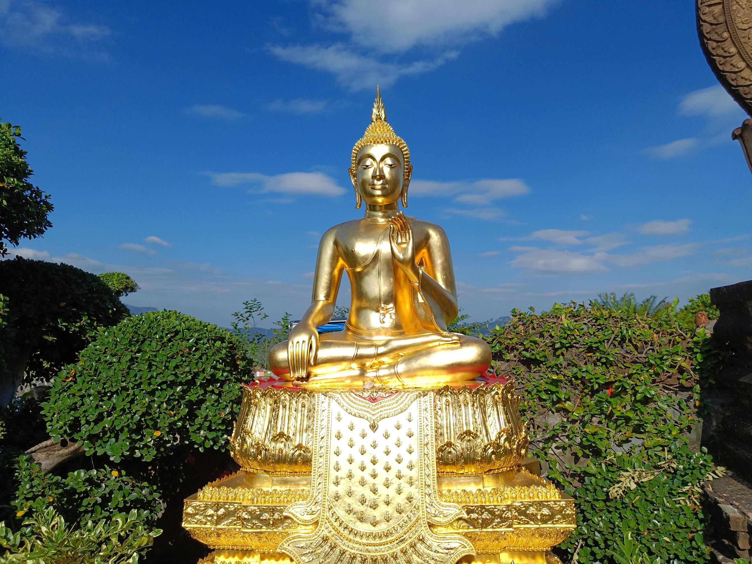 Beautiful Golden Buddha statue against blue sky and clouds in Thailand