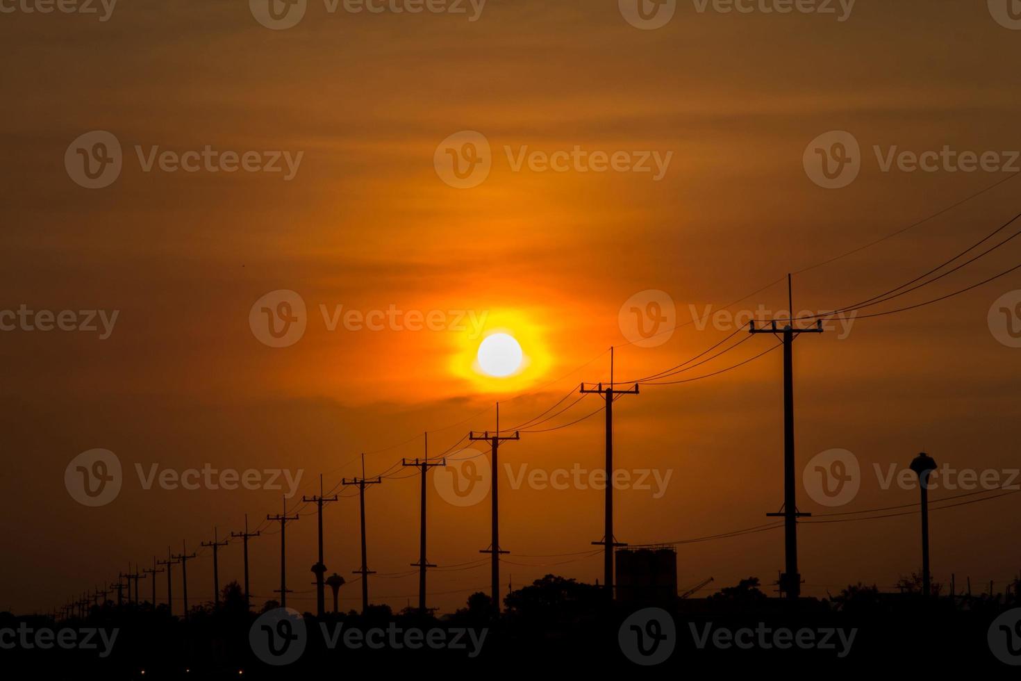 atmosphere in the evening-high voltage pole beside highway and orange sky The big sun that was setting was beautiful as I was on my way home, it was a beautiful romantic atmosphere. photo