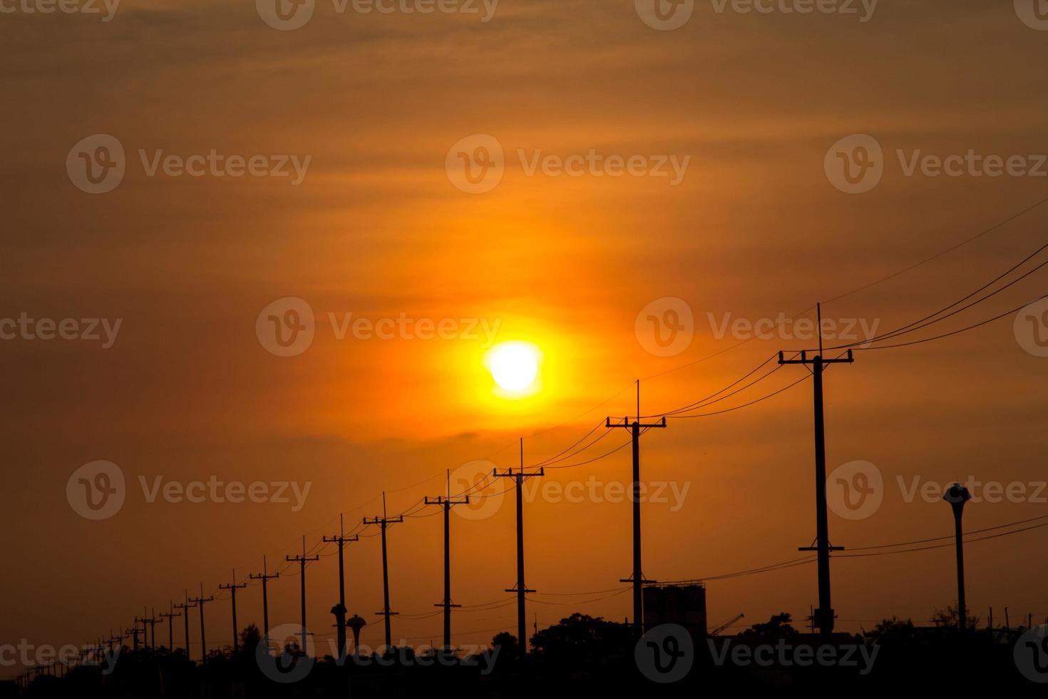 atmosphere in the evening-high voltage pole beside highway and orange sky The big sun that was setting was beautiful as I was on my way home, it was a beautiful romantic atmosphere. photo