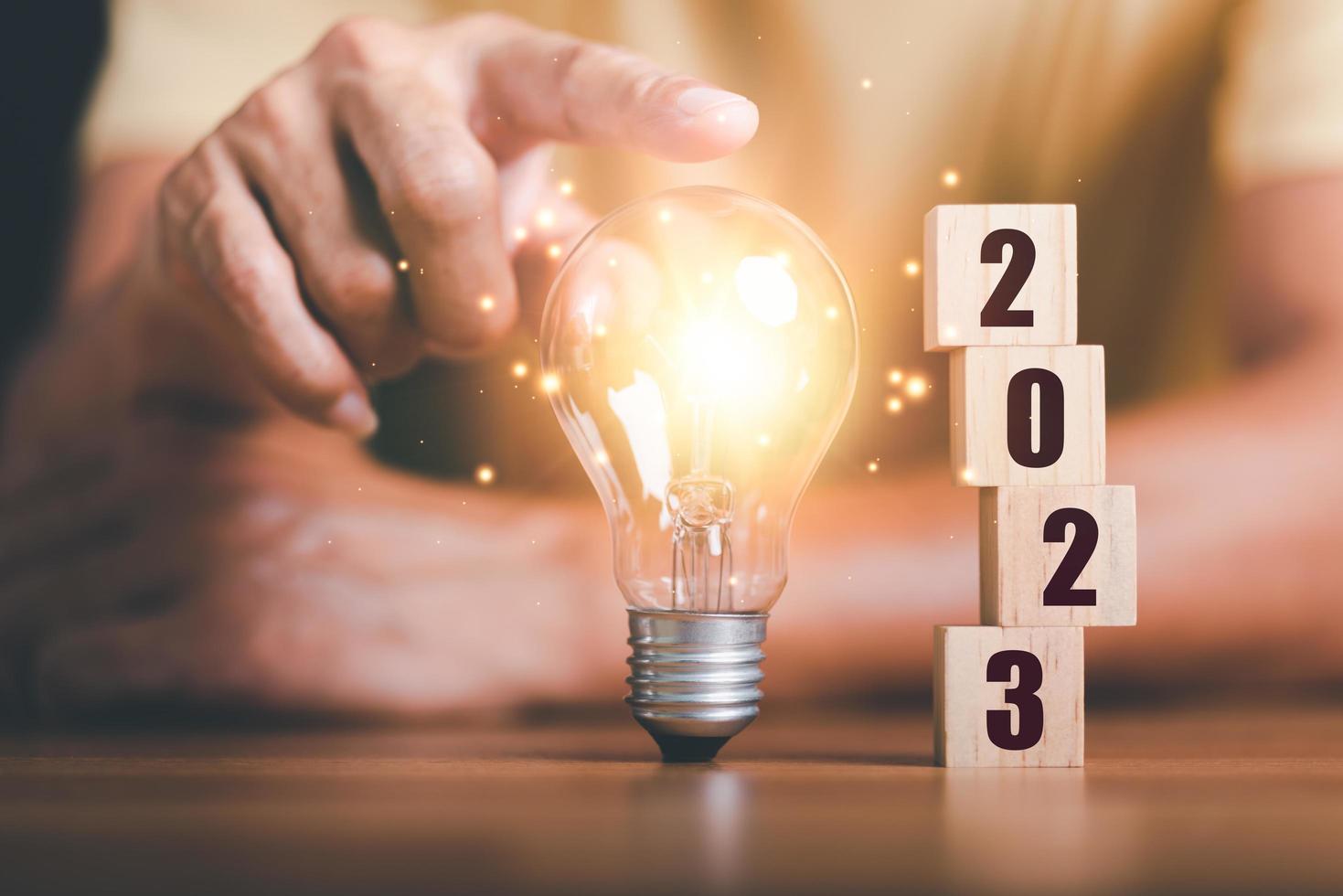 New Year 2023 Beginning Concept,,concept with innovation and inspiration, innovative technology in science concept and modern business development,creative idea,Wooden blocks and light bulbs on table photo