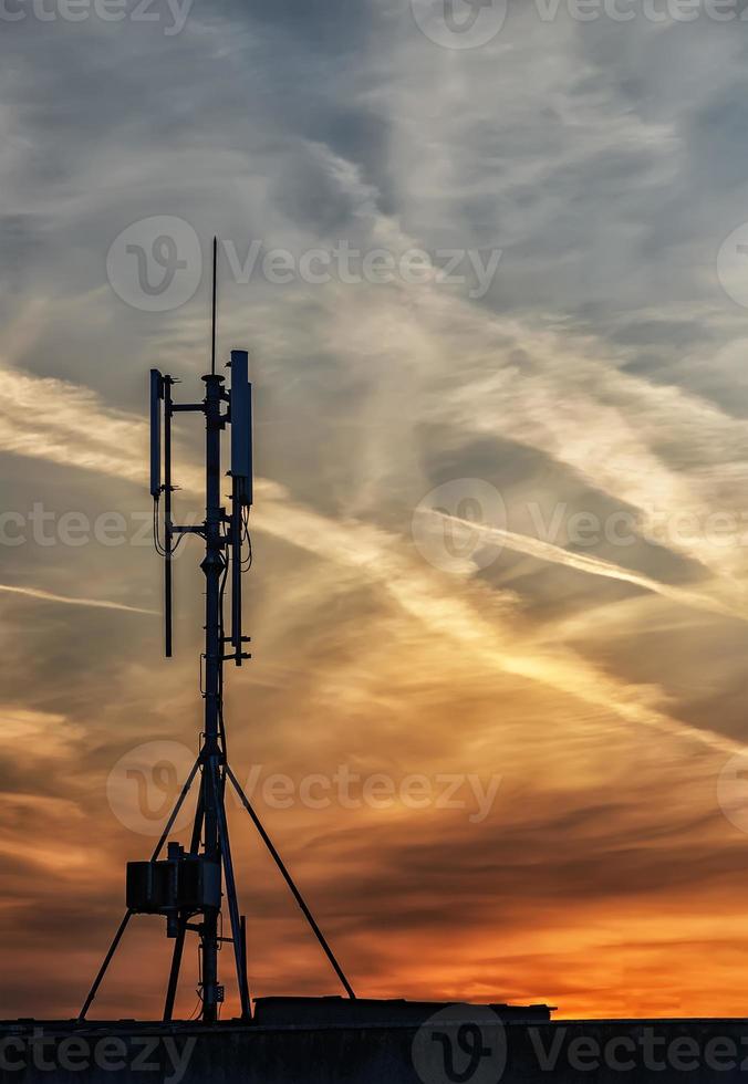 silhouette of GSM transmitters on the roof office building at amazing clouds photo