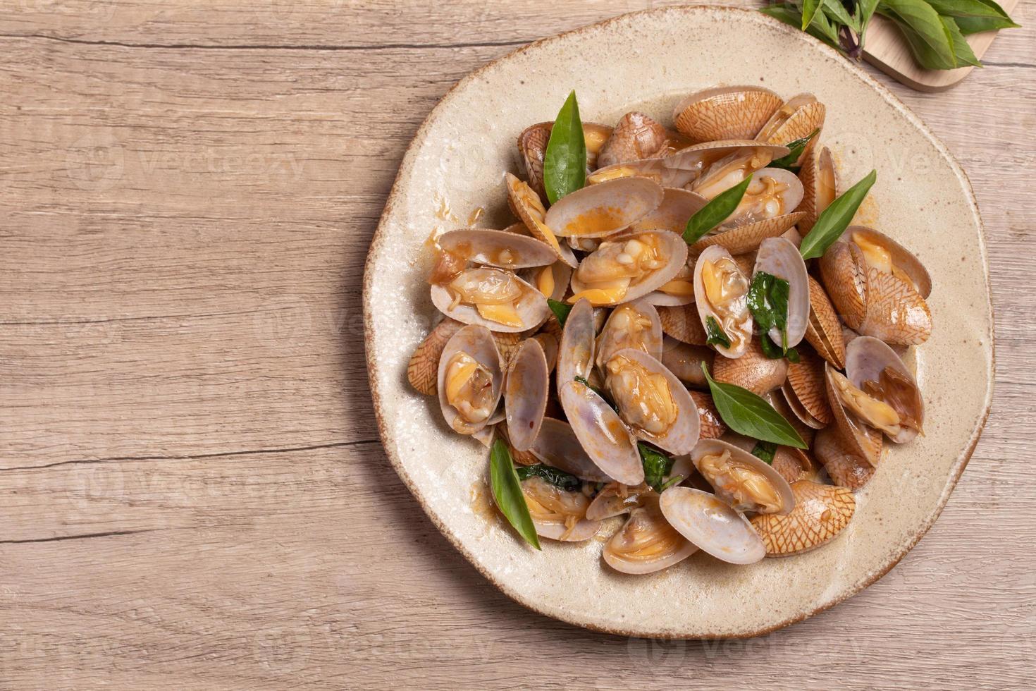Stir fried clams with basil leaves in a white bowl photo