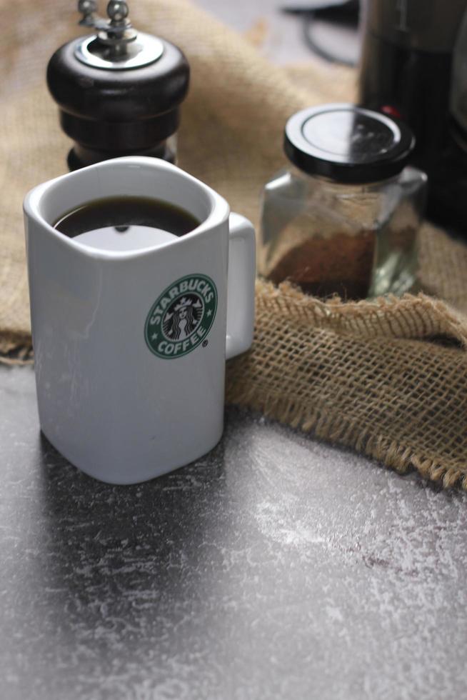 Washington, USA - September 30 2022 - Starbucks Ceramic Mug. Put on the gray table and coffee machine, coffee pot, coffee grinder, ground coffee beans. photo