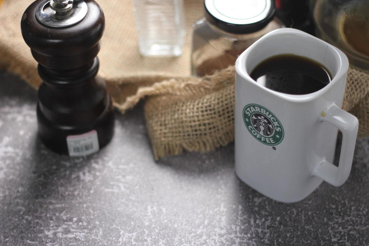 Washington, USA - September 30 2022 - Starbucks Ceramic Mug. Put on the gray table and coffee machine, coffee pot, coffee grinder, ground coffee beans. photo