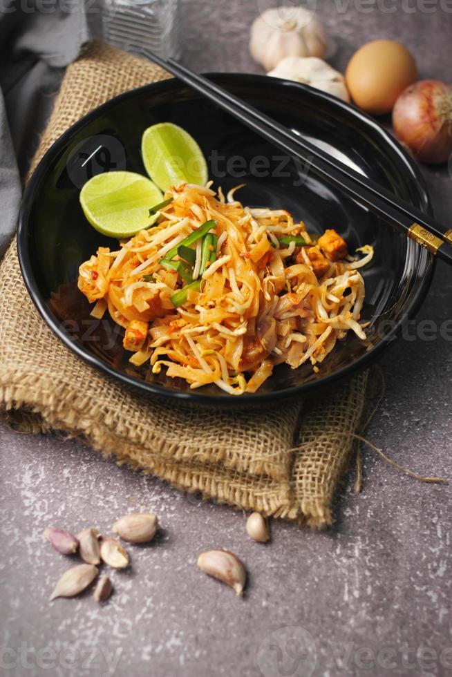 Pad Thai or Thai-style pad Thai served with lime and seasonings In a black plate, it's a food that can be found in street food in Thailand. photo