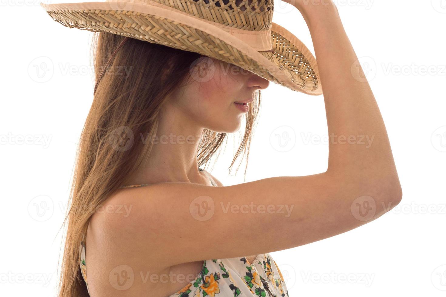 Portrait of a young brunette who covers her face and hat stands sideways isolated on a white background photo
