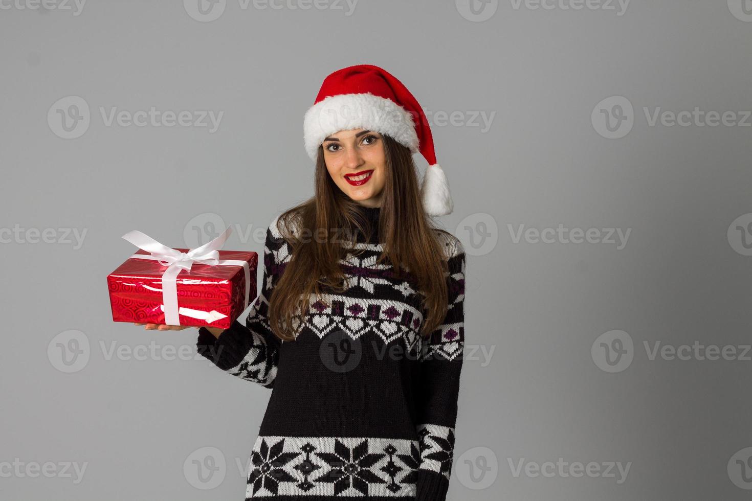 woman in warm sweater and santa hat with red gift photo