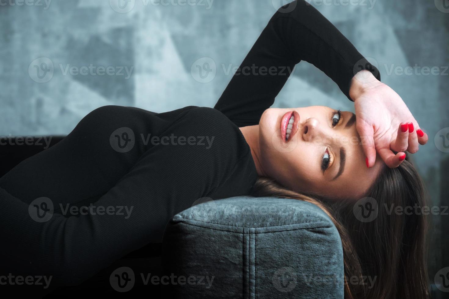 Charming woman in black dress on a couch photo