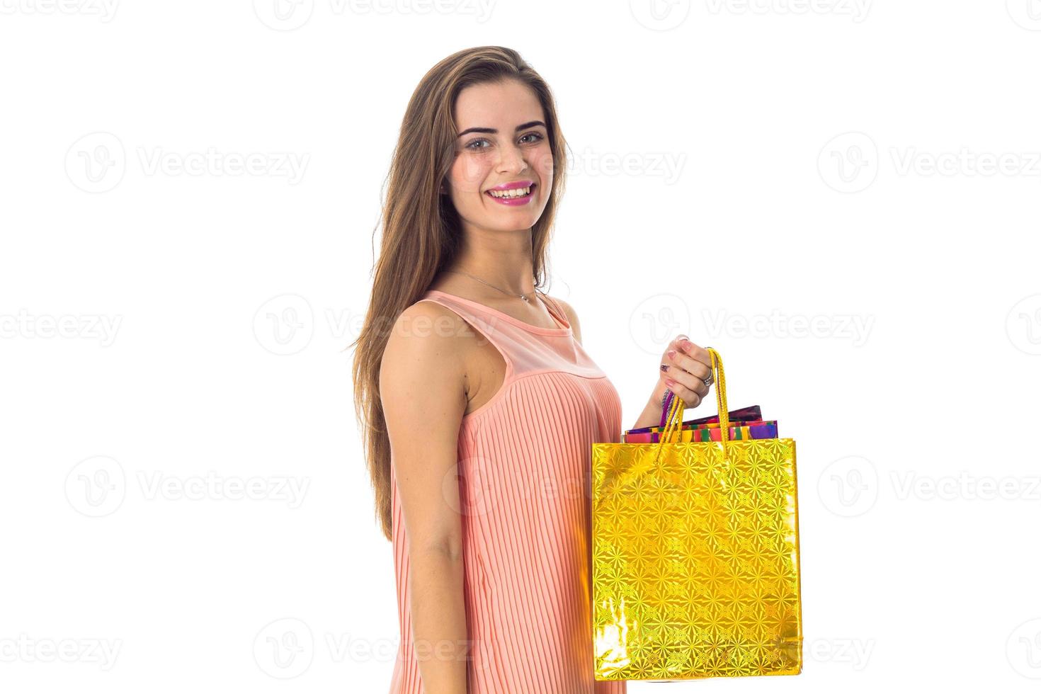 beautiful girl is worth turning sideways smiles and holds in his hand a yellow package isolated on white background photo