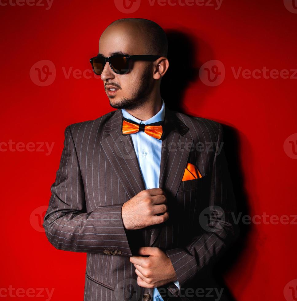 Nice man in sunglasses and suit on red background photo