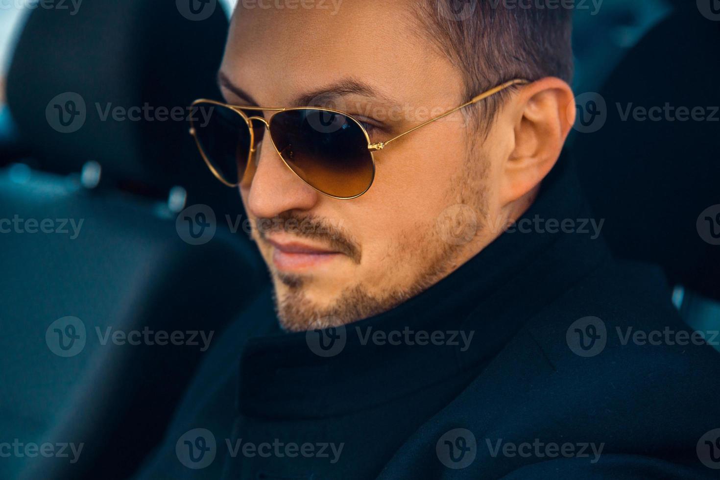 Horizontal portrait of adult caucasian fashionable male with sunglasses in car photo