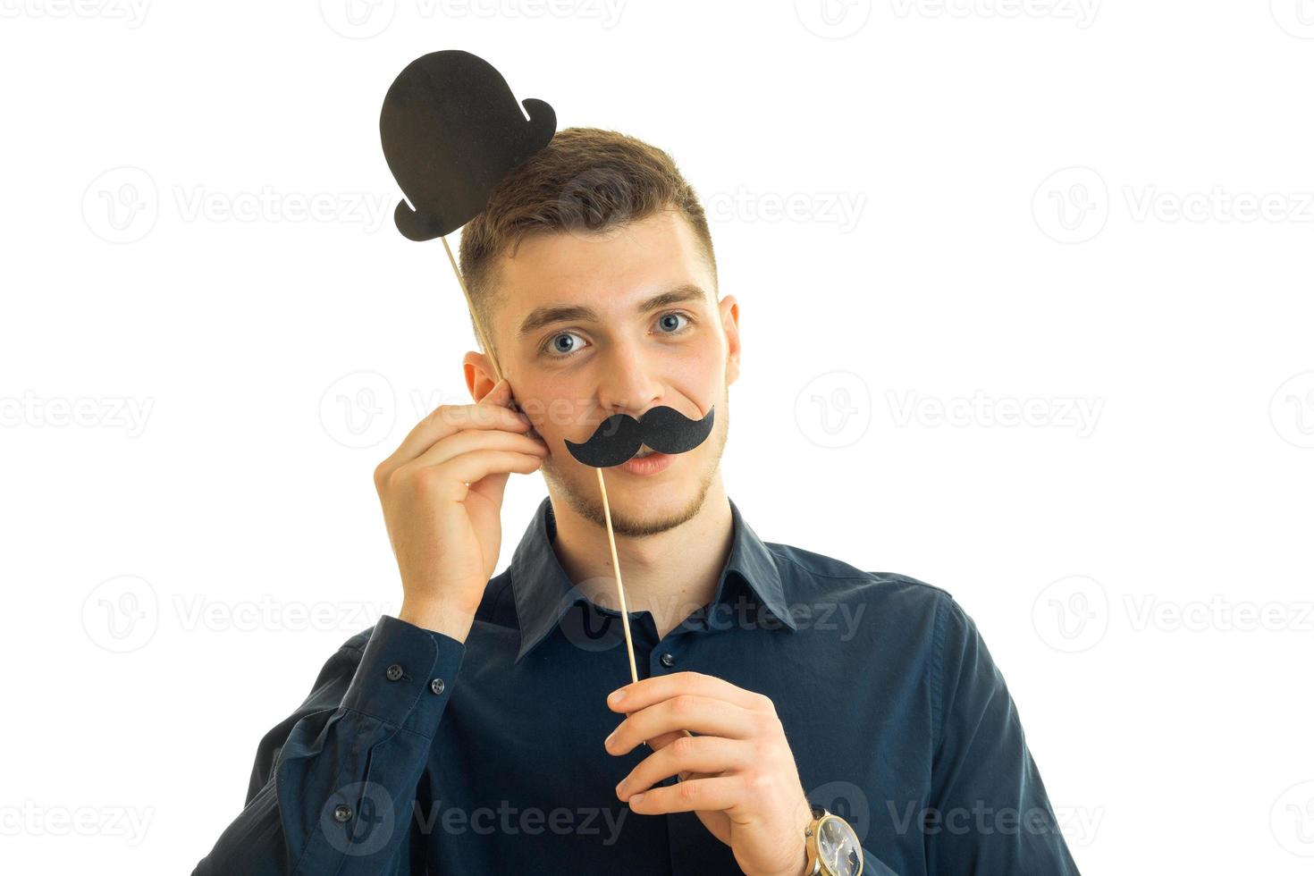 young handsome guy keeps near the face, paper mustache and a hat photo