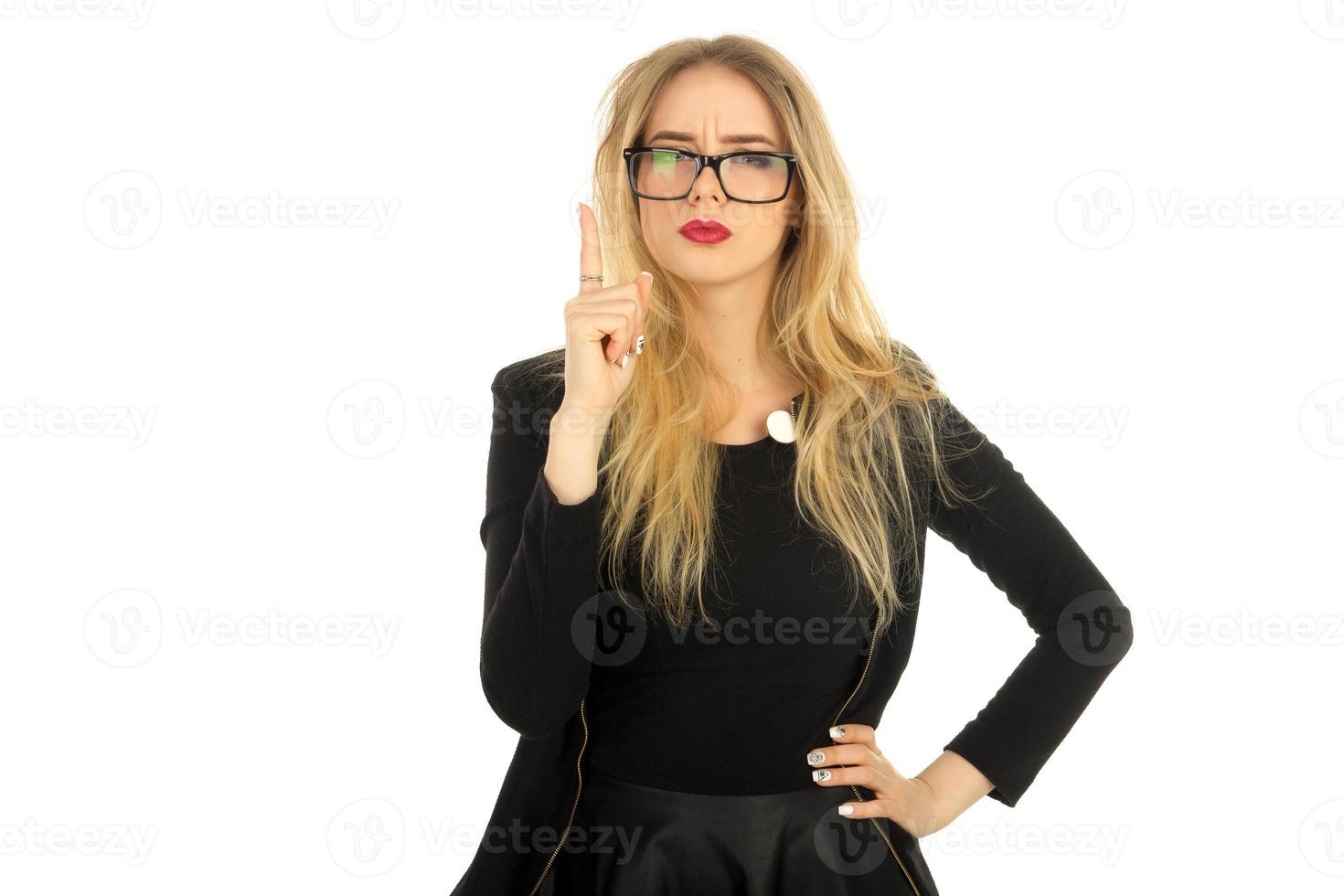 chica con traje negro y gafas señala con el dedo hacia arriba foto