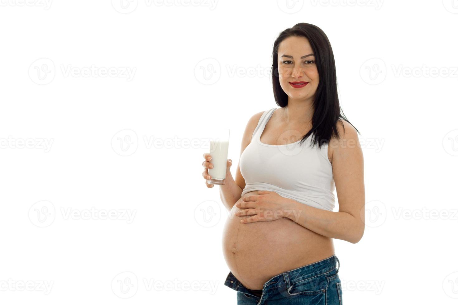 Young cheerful pregnant mother isolated on white background in studio posing with glass of milk photo
