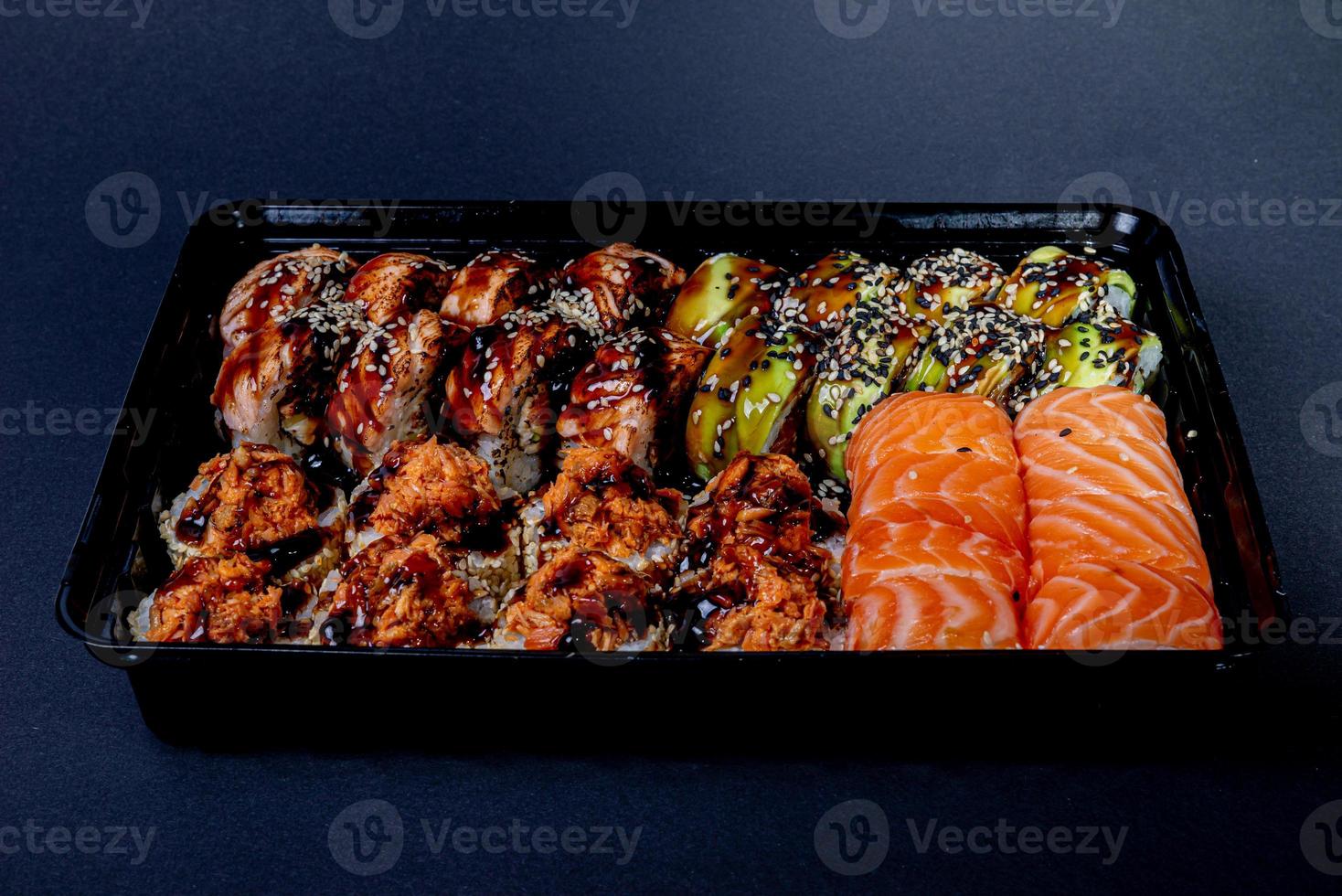 Traditional delicious fresh sushi roll set on a black background with reflection. Sushi roll with rice, cream cheese, avocado, salmon, sesame. Philadelphia. Sushi menu. Japanese kitchen, photo