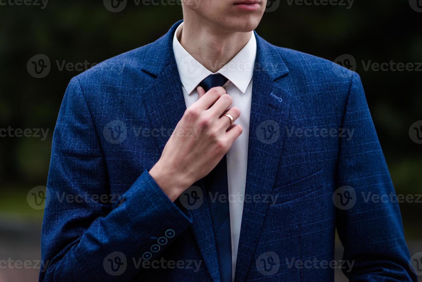 hombre elegante atando su corbata sobre camisa negra. corbata de ajuste. negro y violeta. vestidor de hombre de negocios joven, aislado sobre fondo negro. novio ajustando su corbata. foto