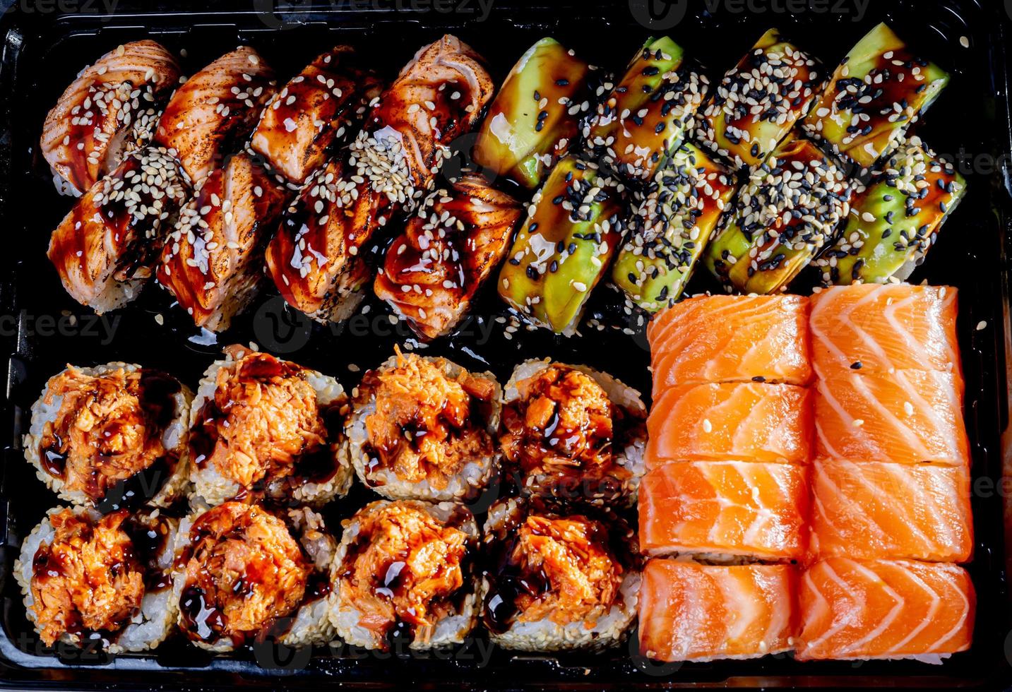 Traditional delicious fresh sushi roll set on a black background with reflection. Sushi roll with rice, cream cheese, avocado, salmon, sesame. Philadelphia. Sushi menu. Japanese kitchen, photo