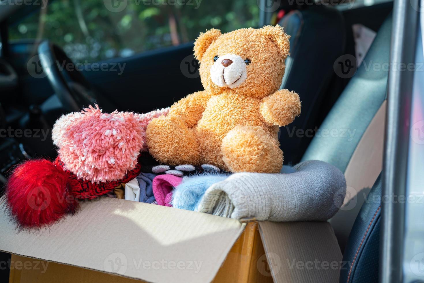 Volunteer woman provide clothing donation box with used clothes and doll at home to support help for refugee, homeless or poor people in the world. photo