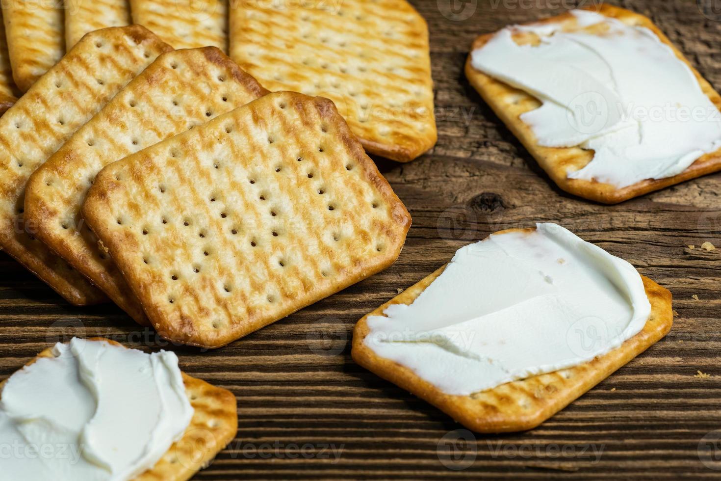 galletas untadas con queso como refrigerio ligero en una tabla de madera foto