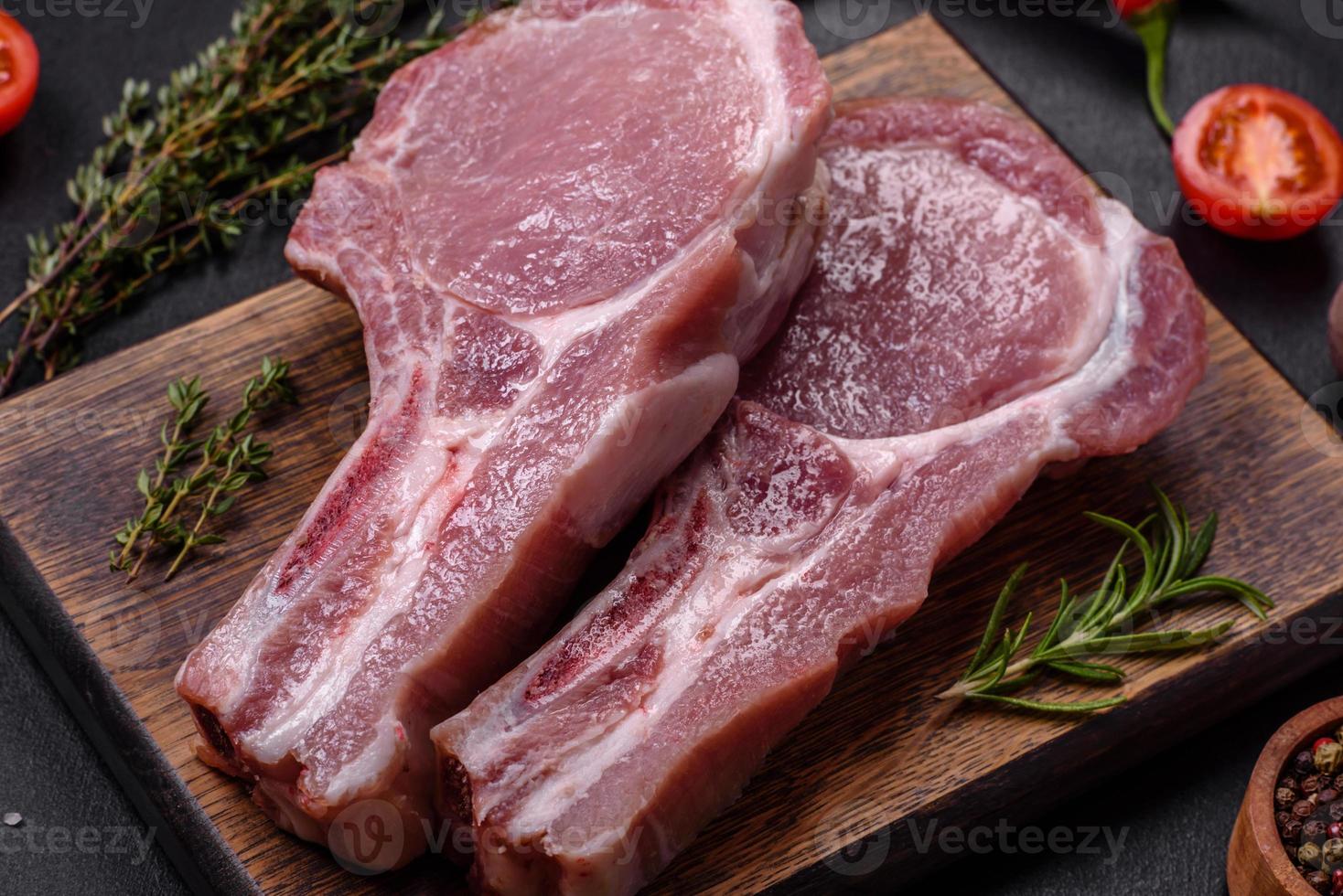 Fresh raw pork meat on the ribs with spices and herbs on a wooden cutting board photo