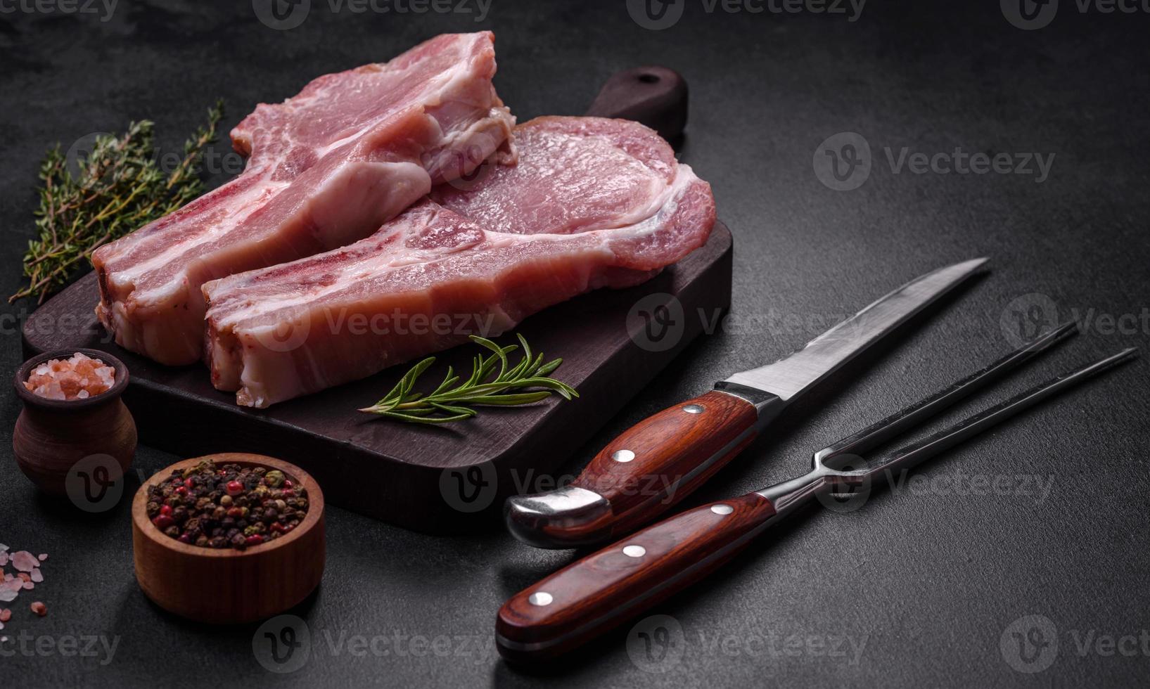 carne de cerdo cruda fresca en las costillas con especias y hierbas en una tabla de cortar de madera foto