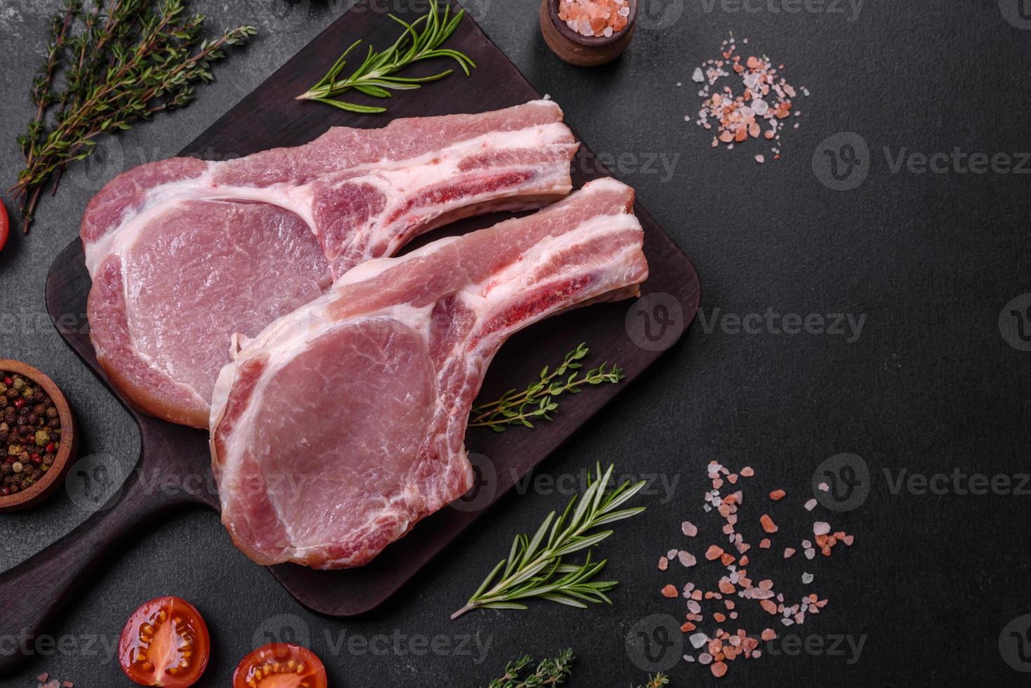 Fresh raw pork meat on the ribs with spices and herbs on a wooden cutting board photo