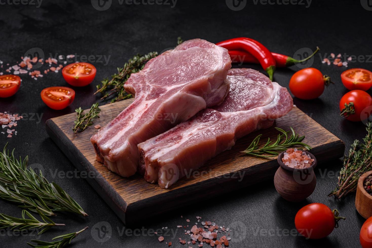 carne de cerdo cruda fresca en las costillas con especias y hierbas en una tabla de cortar de madera foto