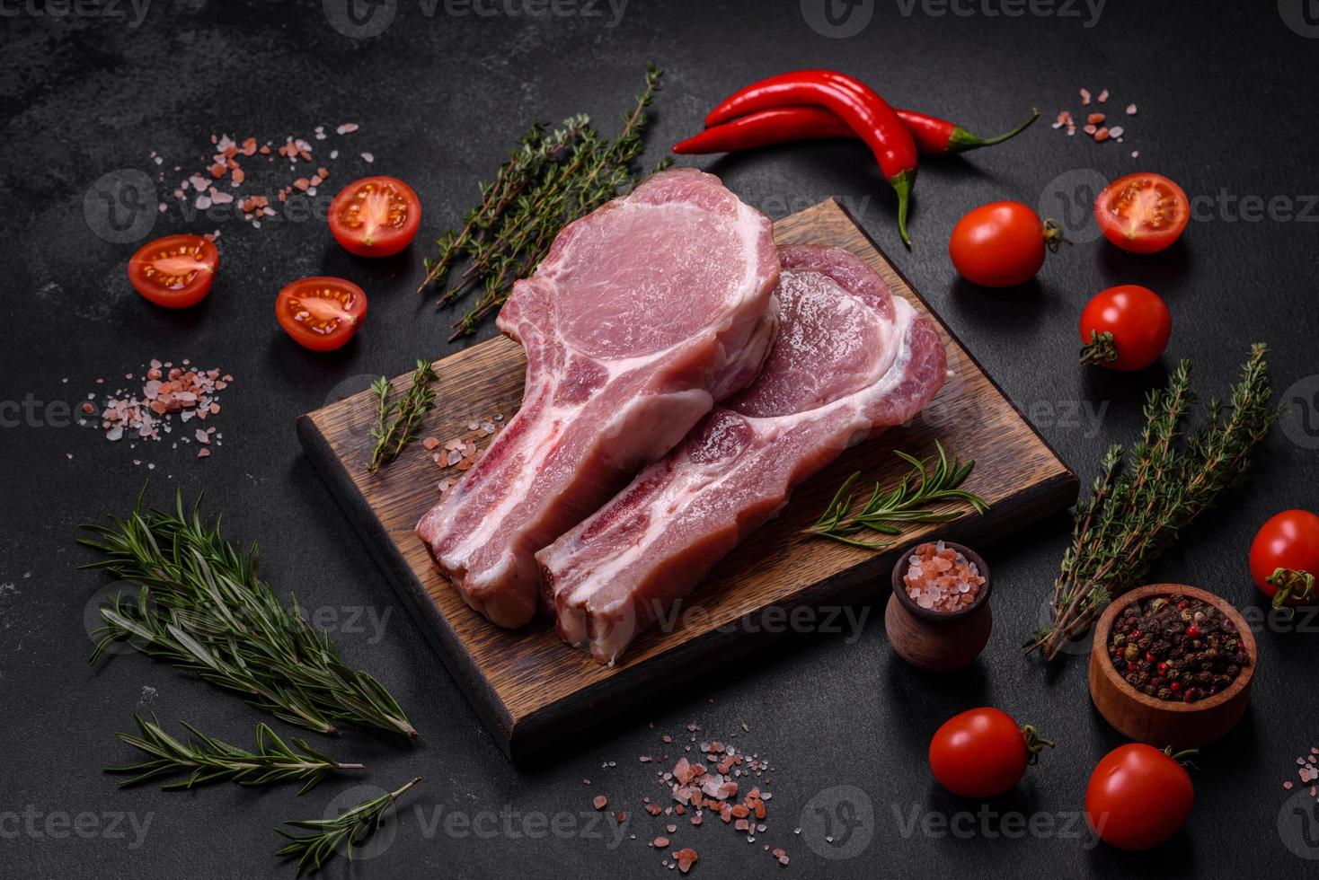 carne de cerdo cruda fresca en las costillas con especias y hierbas en una tabla de cortar de madera foto