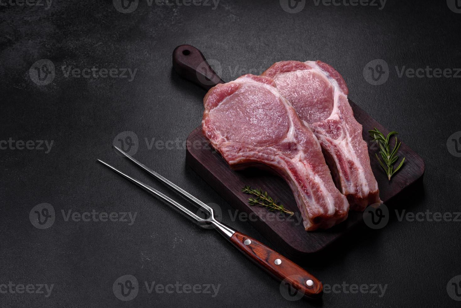 Fresh raw pork meat on the ribs with spices and herbs on a wooden cutting board photo