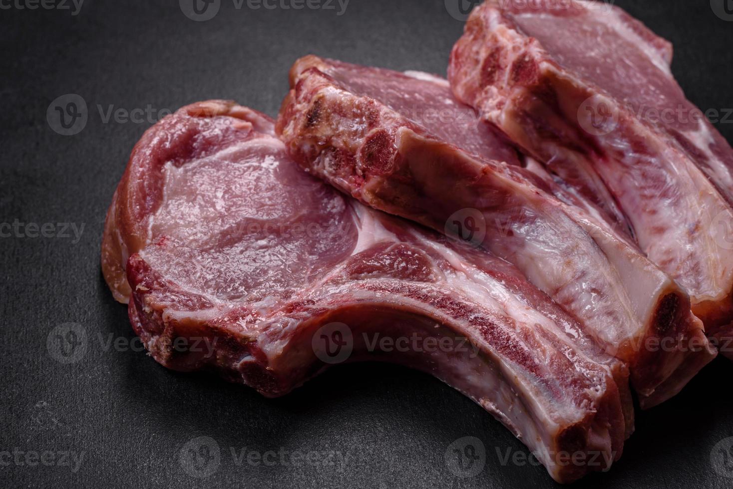 carne de cerdo cruda fresca en las costillas con especias y hierbas en una tabla de cortar de madera foto