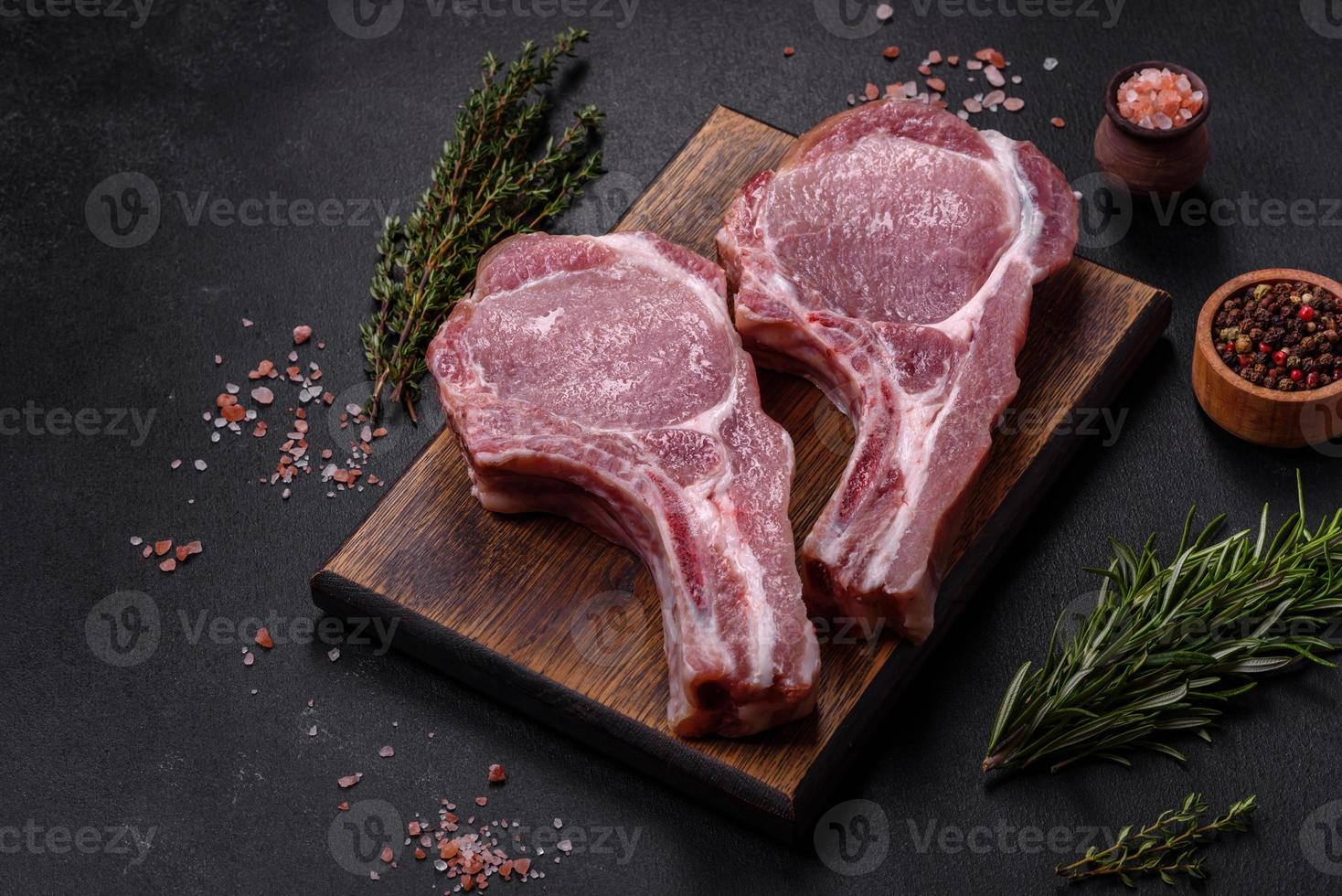 Fresh raw pork meat on the ribs with spices and herbs on a wooden cutting board photo