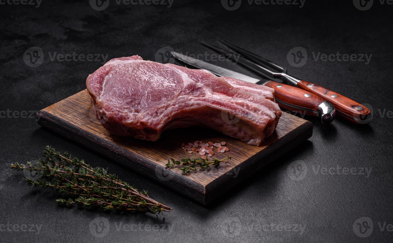 Fresh raw pork meat on the ribs with spices and herbs on a wooden cutting board photo