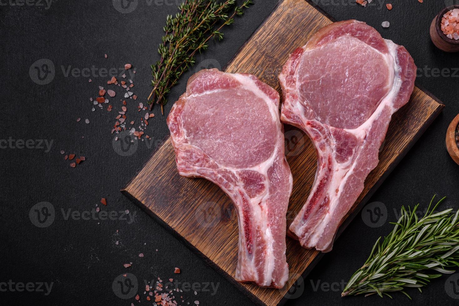 carne de cerdo cruda fresca en las costillas con especias y hierbas en una tabla de cortar de madera foto