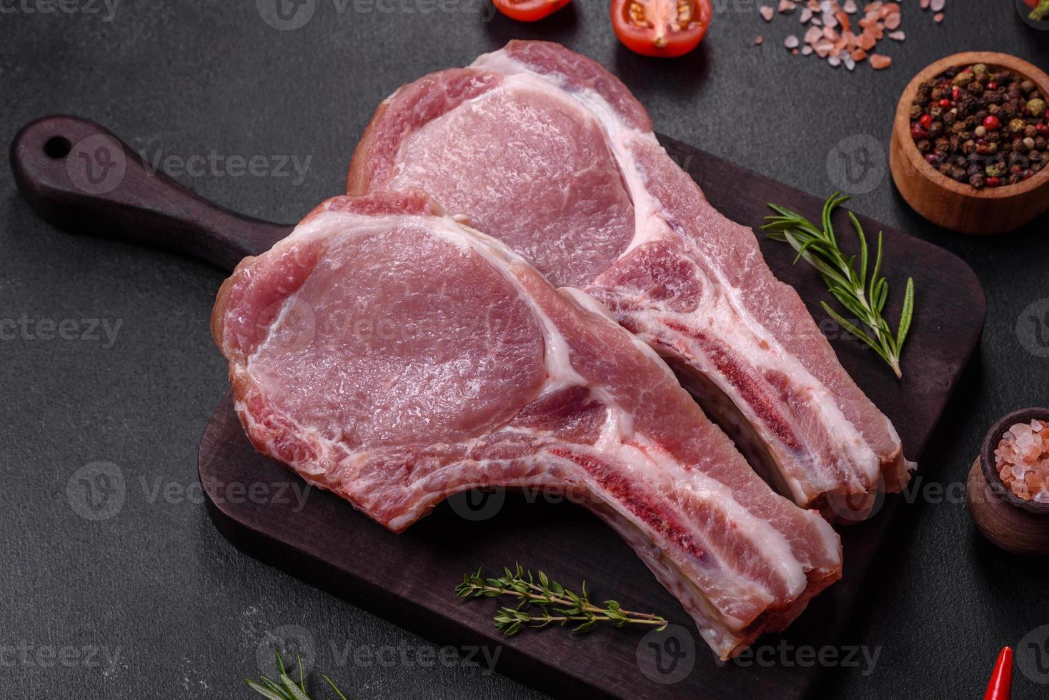 Fresh raw pork meat on the ribs with spices and herbs on a wooden cutting board photo