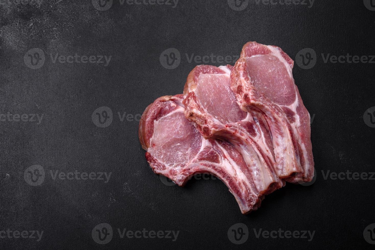 carne de cerdo cruda fresca en las costillas con especias y hierbas en una tabla de cortar de madera foto