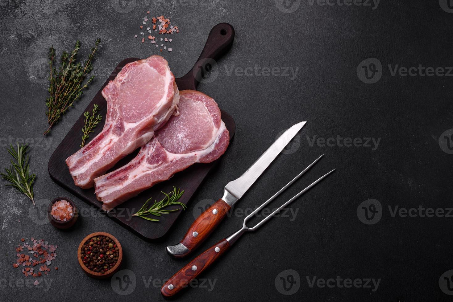 Fresh raw pork meat on the ribs with spices and herbs on a wooden cutting board photo