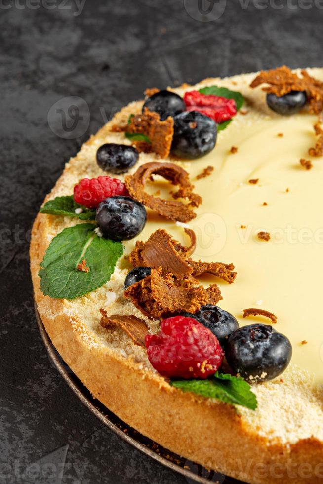 Homemade classic cheesecake on dark background. Decorating sweet cake with fresh berries photo