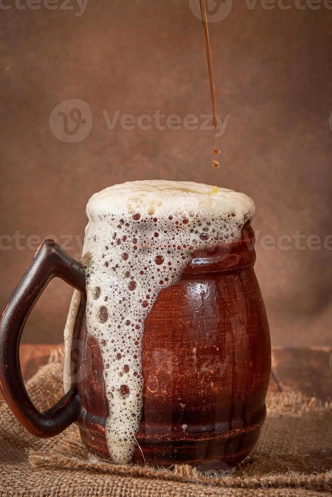 Beer clay brown mug with kvass on a wooden table on a dark background. A traditional drink made of bread, sourdough photo