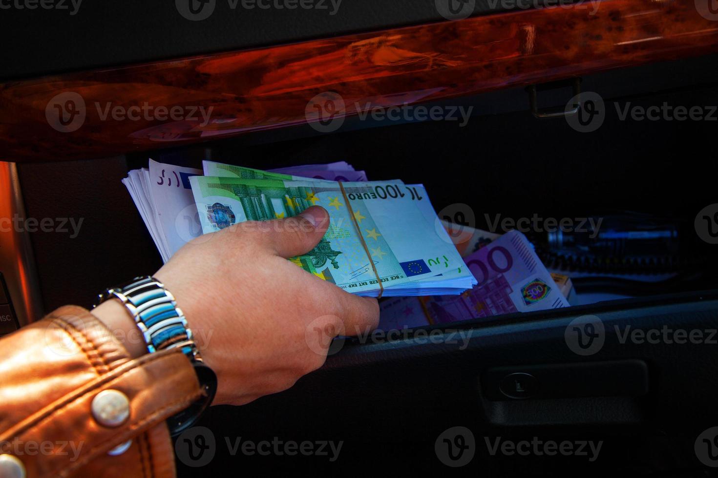 macro photo of a man's hand taking on glove compartment of cars a lot of money EUR