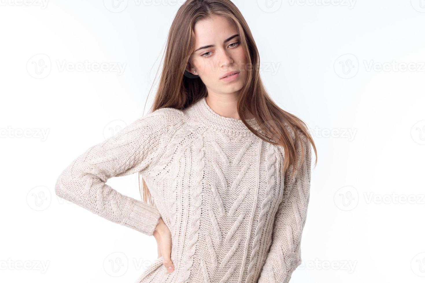 young girl in white sweater keeps her hand on the side and looks down photo