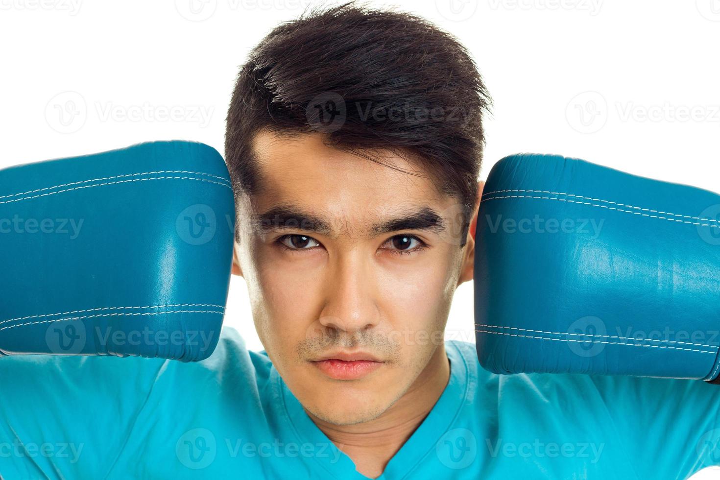portrait of young sports man posing in blue boxing gloves in studio isolated on white background photo