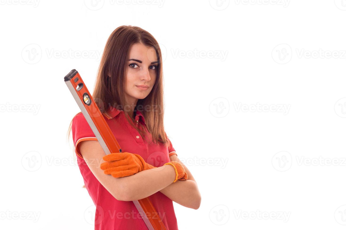 attractive young brunette builder girl in uniform makes renovation with tools in her hands isolated on white background photo