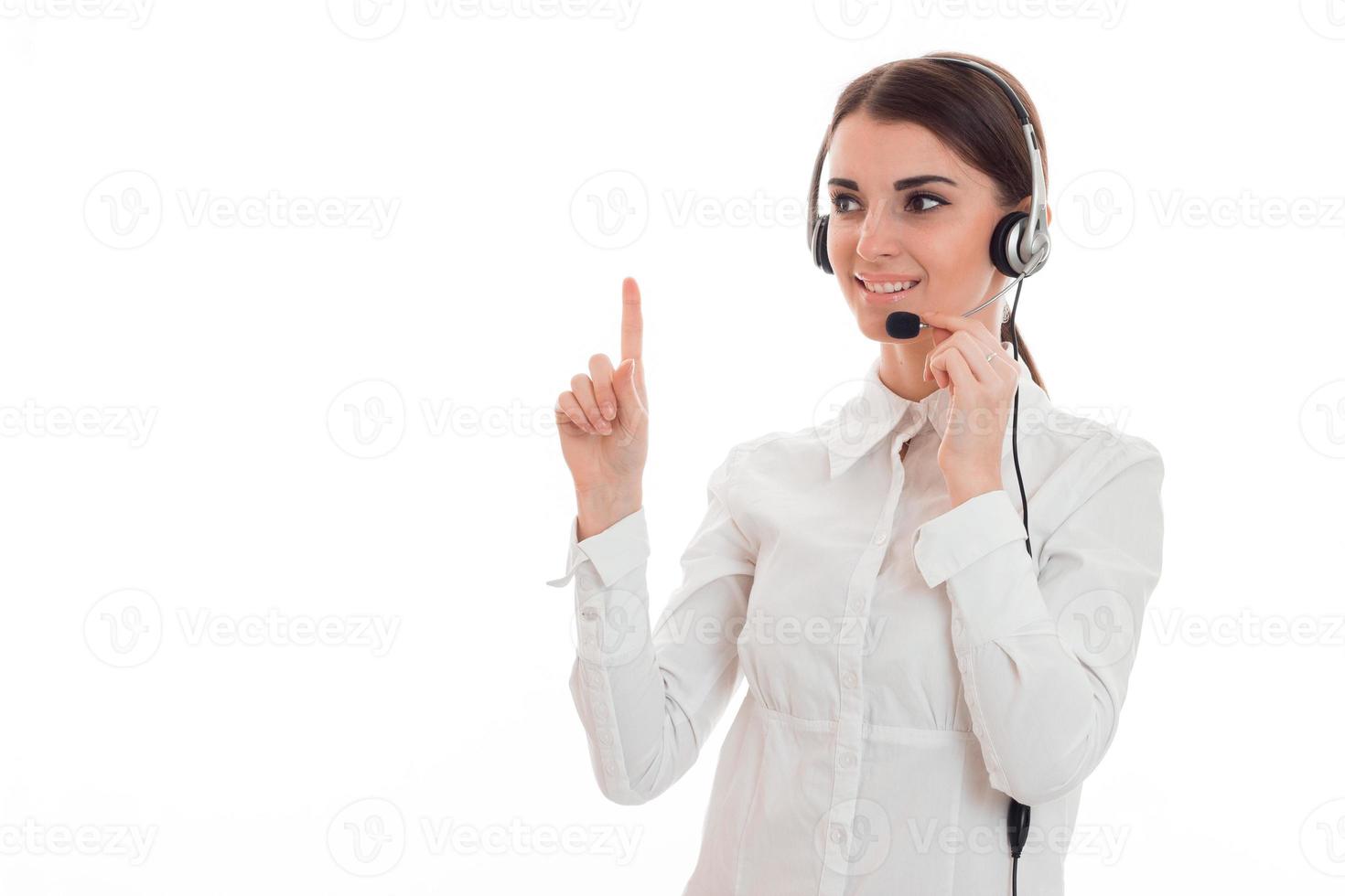 young girl in white shirt and headphones with microphone looks away and raised a finger up photo