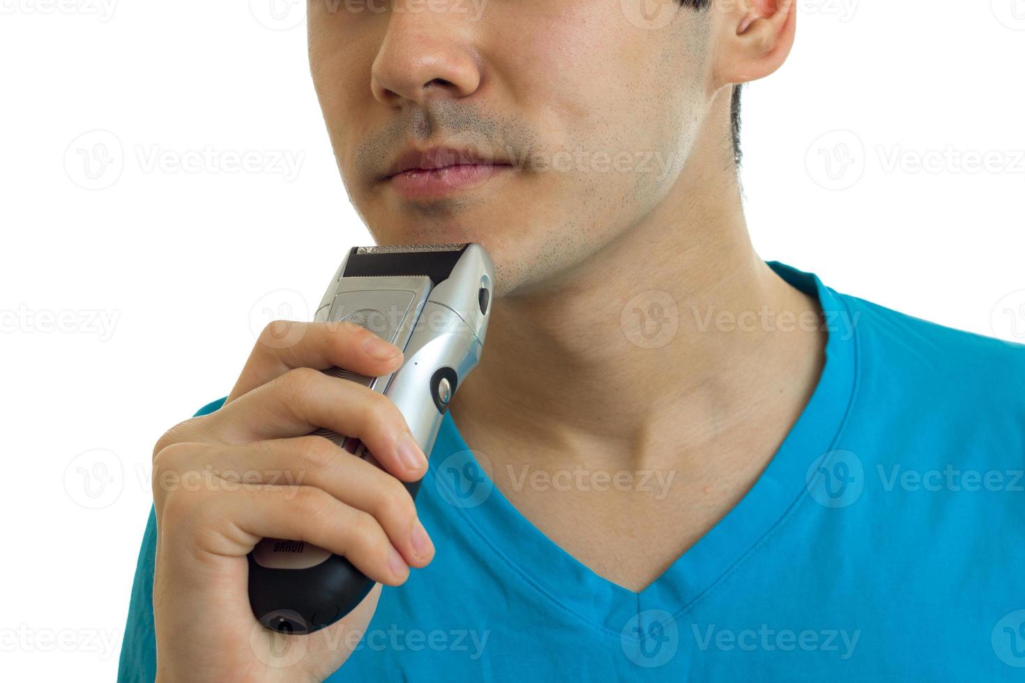 the face of the young guy who shaves his beard trimmer close-up photo