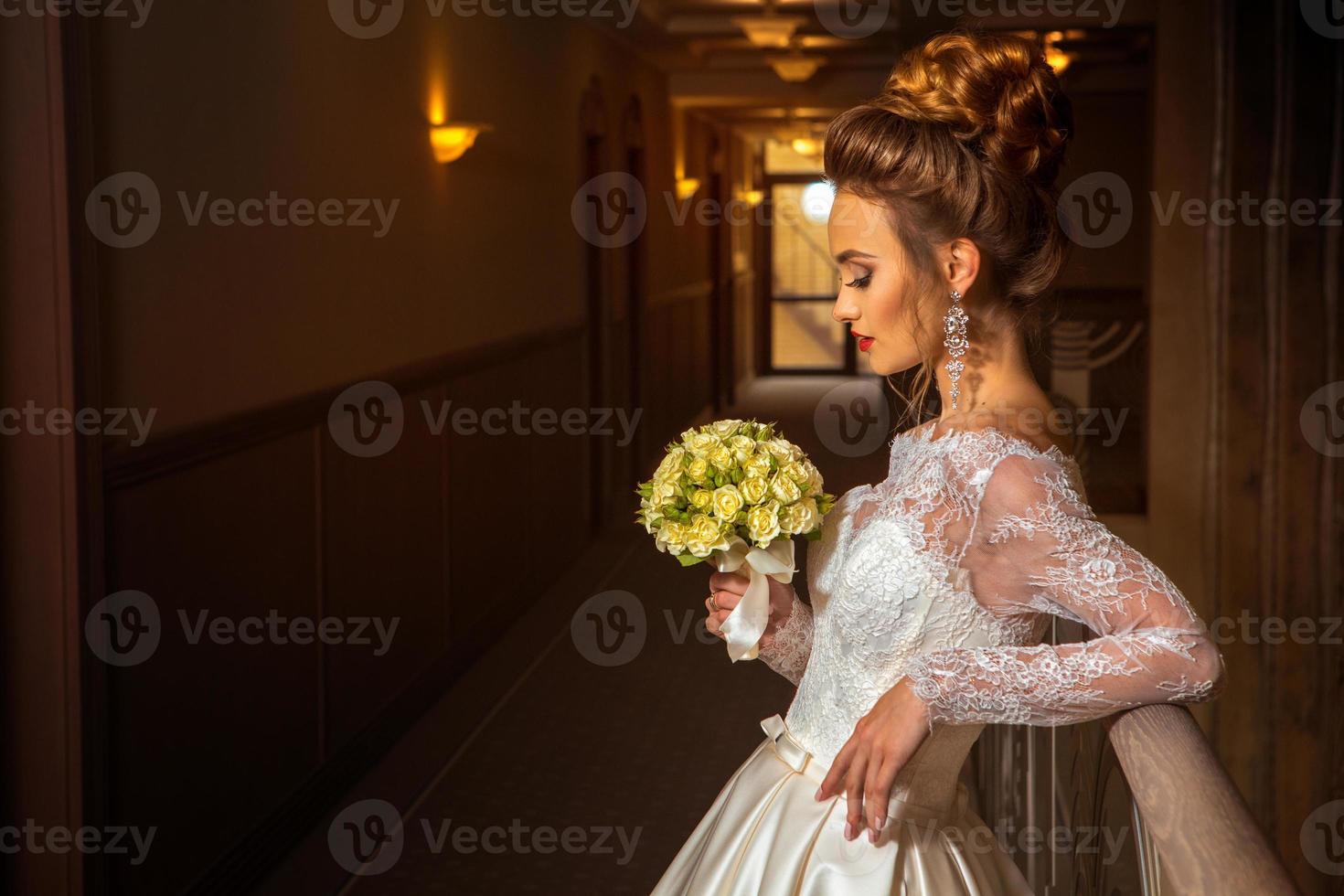 hermosa novia rubia en vestido de novia de moda con ramo de rosas foto