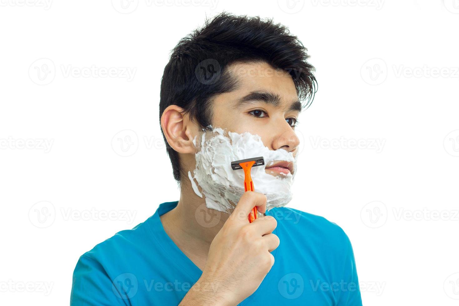 Portrait of a handsome young guy who caused the foam to your face and shaves his beard photo