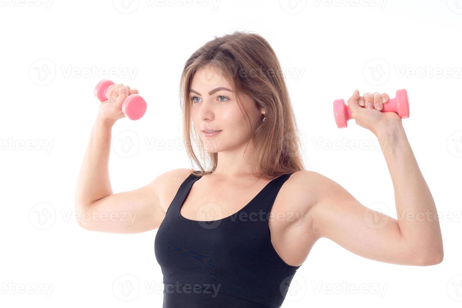 sports girl in a black T-shirt turned sideways and clenching his two arms with dumbbells photo