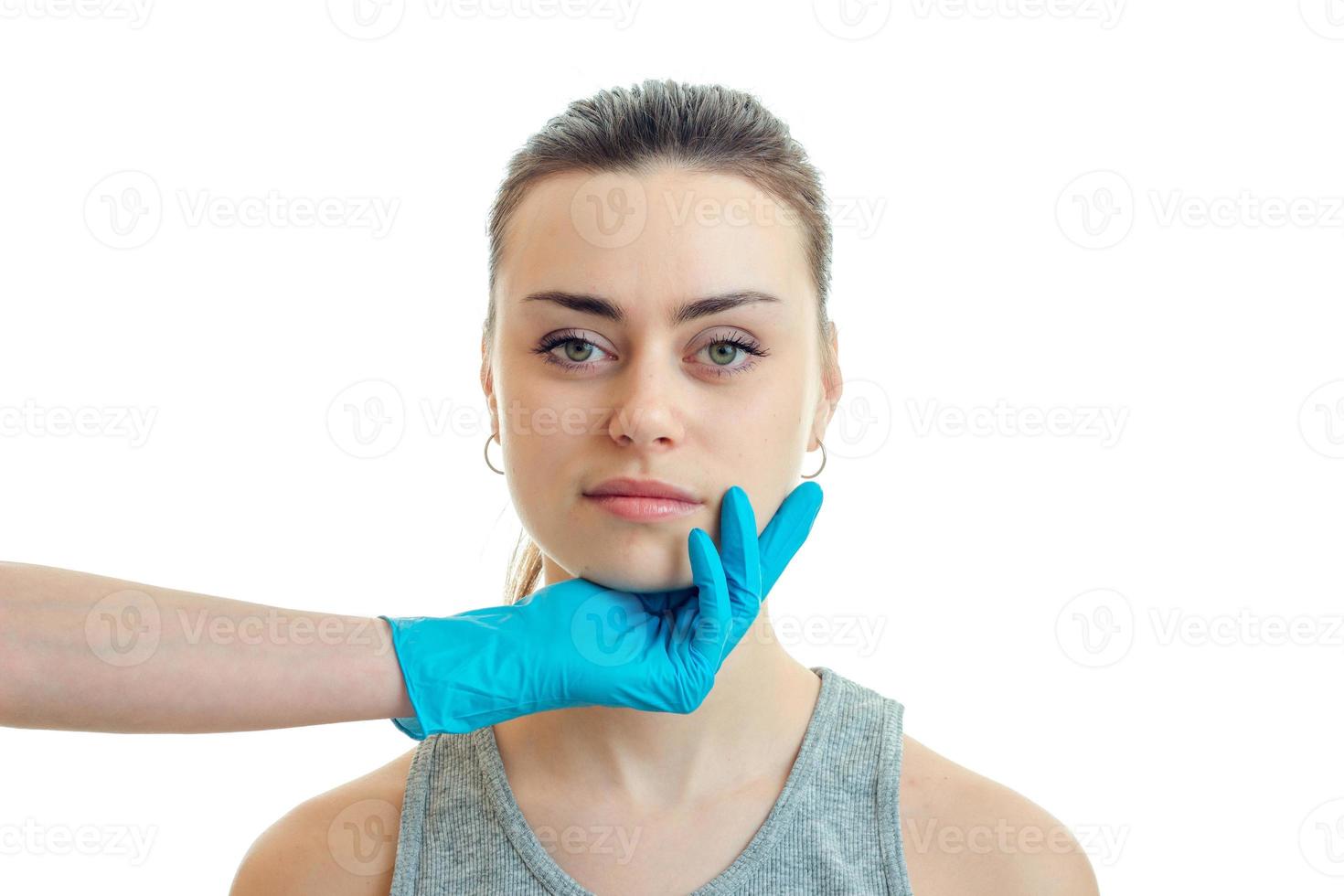 cosmetologist in a blue glove keeps the Chin from a young beautiful girl close-up photo