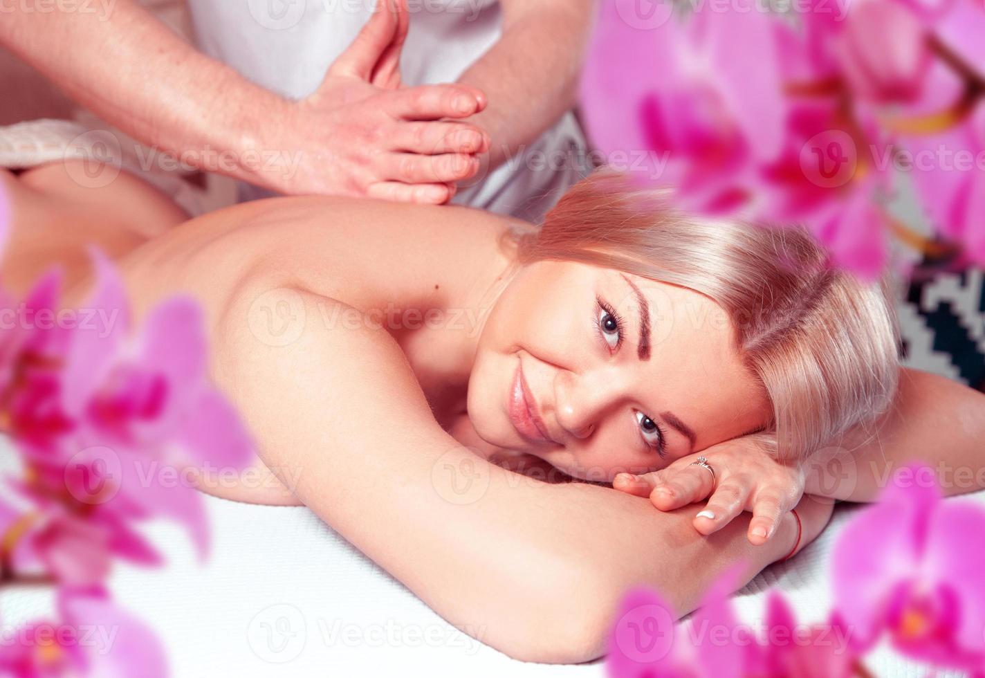 Happy young blonde girl relaxing in spa massage salon photo